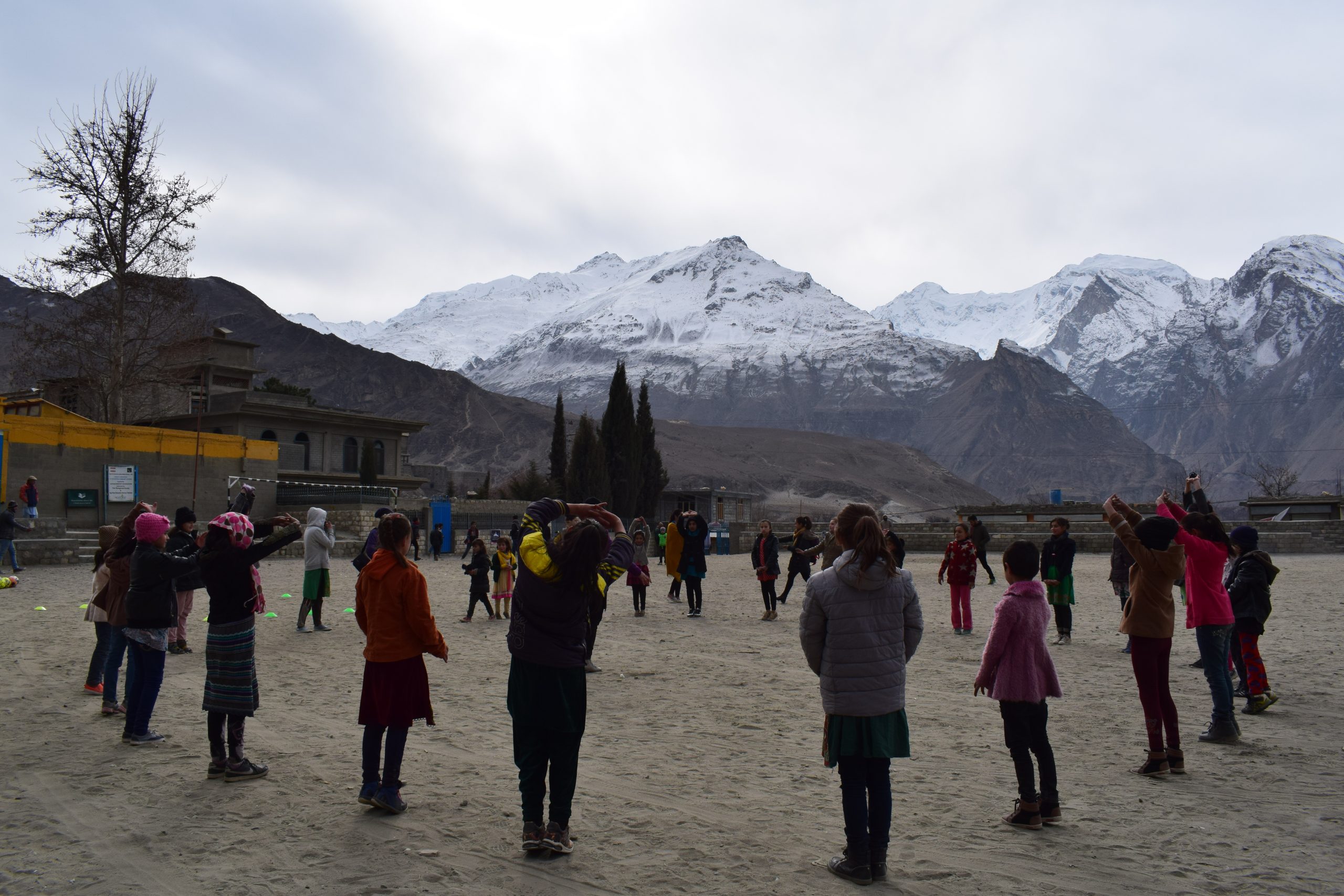 The footballers of Al Shams Women's FC in a circle with the mountains as a back drop